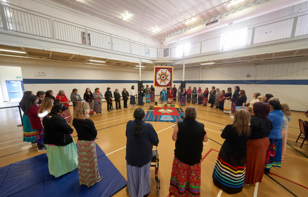 Many women stand in a circle as the leader at the top of the circle performs the ceremony.